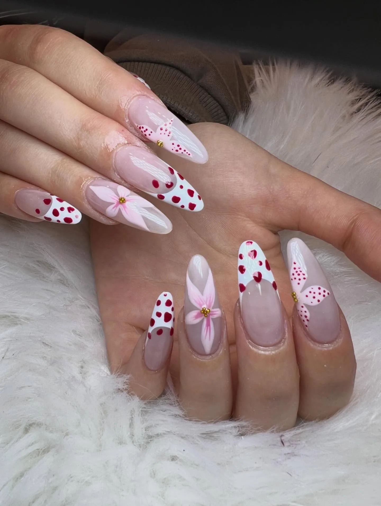Nude almond nails with red-dot French tips and pink lily art