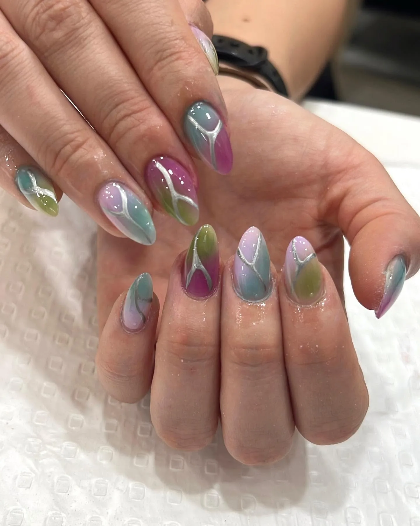 Pastel aura swirl nails — green, pink and blue with silver linework