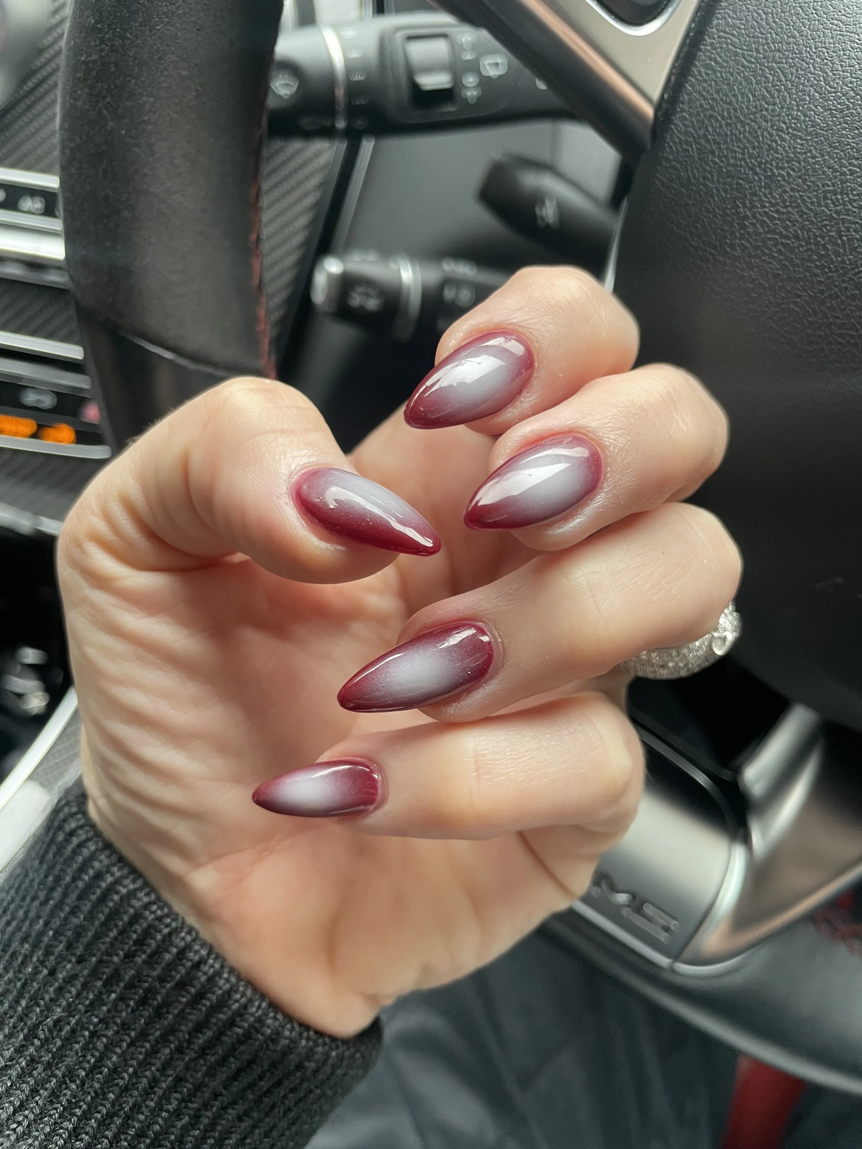 Burgundy and wine ombre almond nails, hand on a car steering wheel