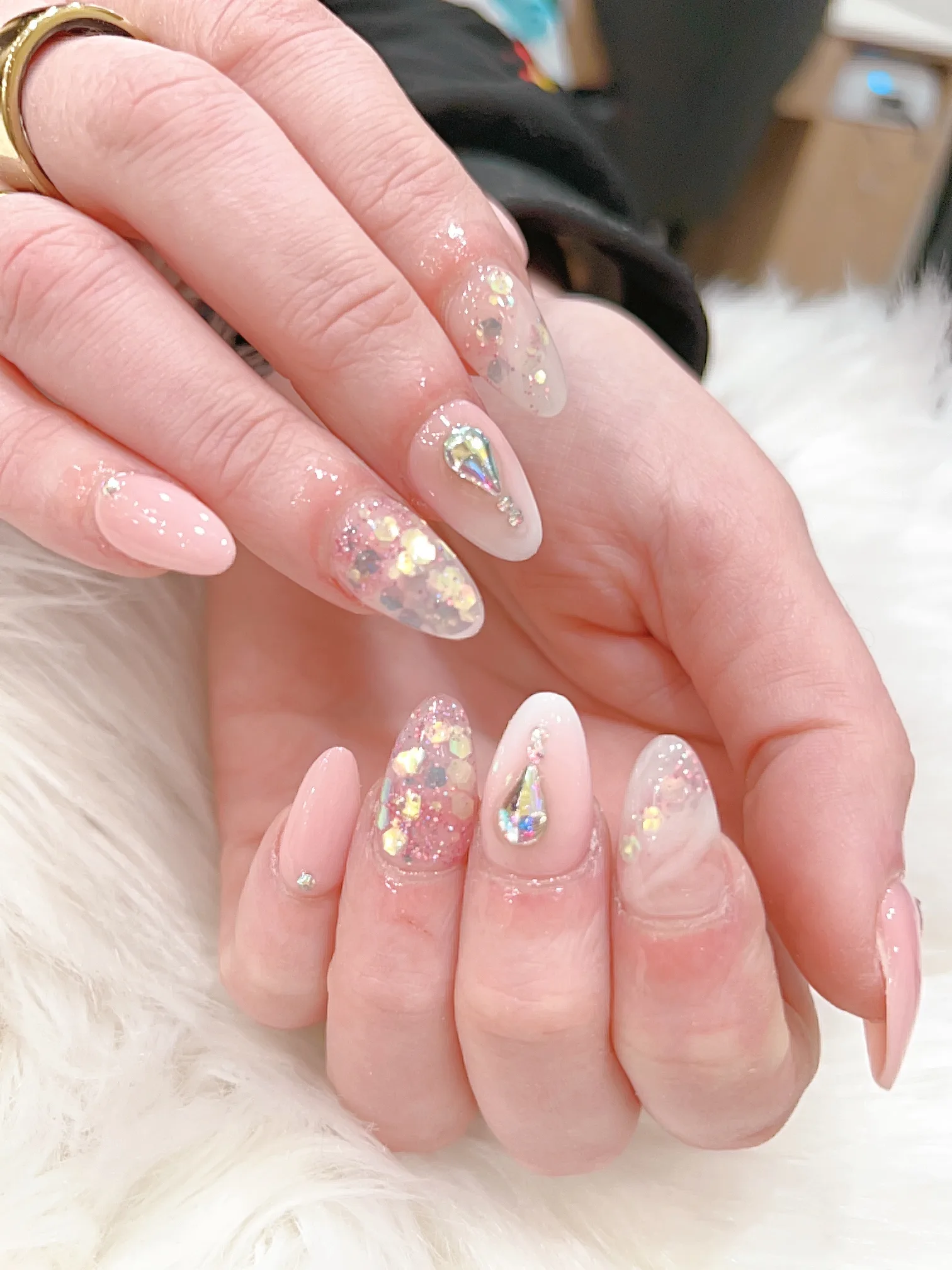 Nude pink almond nails with iridescent confetti glitter and gem droplets