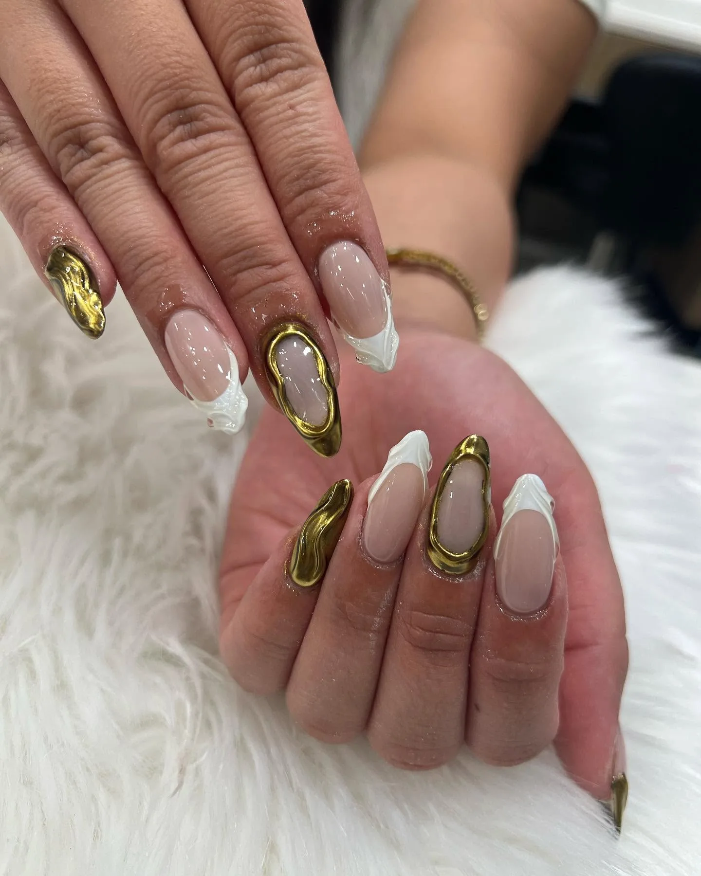 Nude almond nails with gold molten oval frames and white French swirl