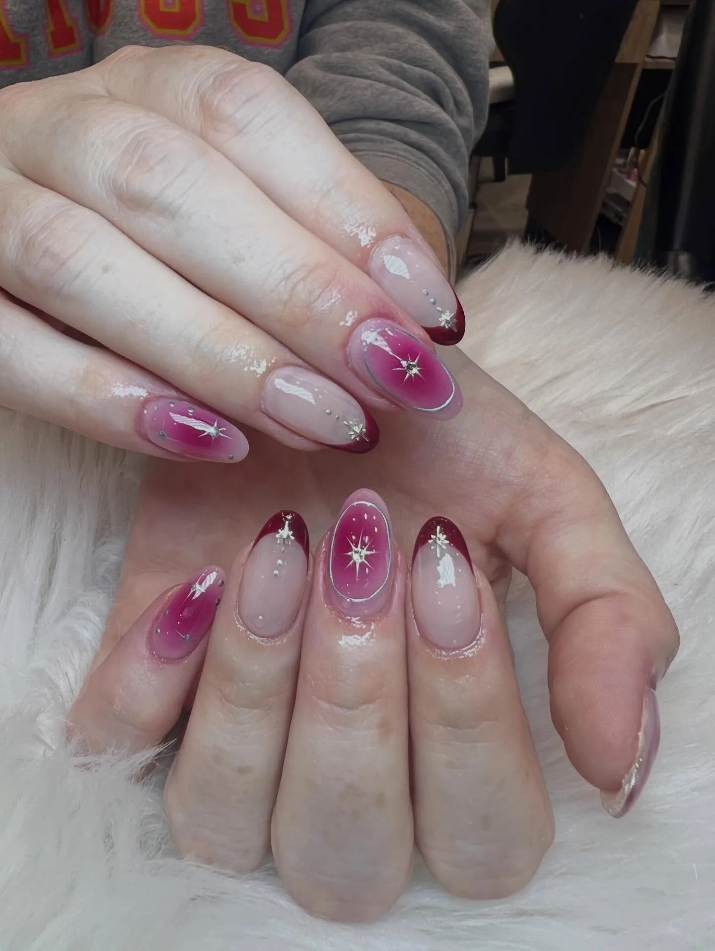 Pink to burgundy ombre almond nails with silver star-bursts, feather art and gems